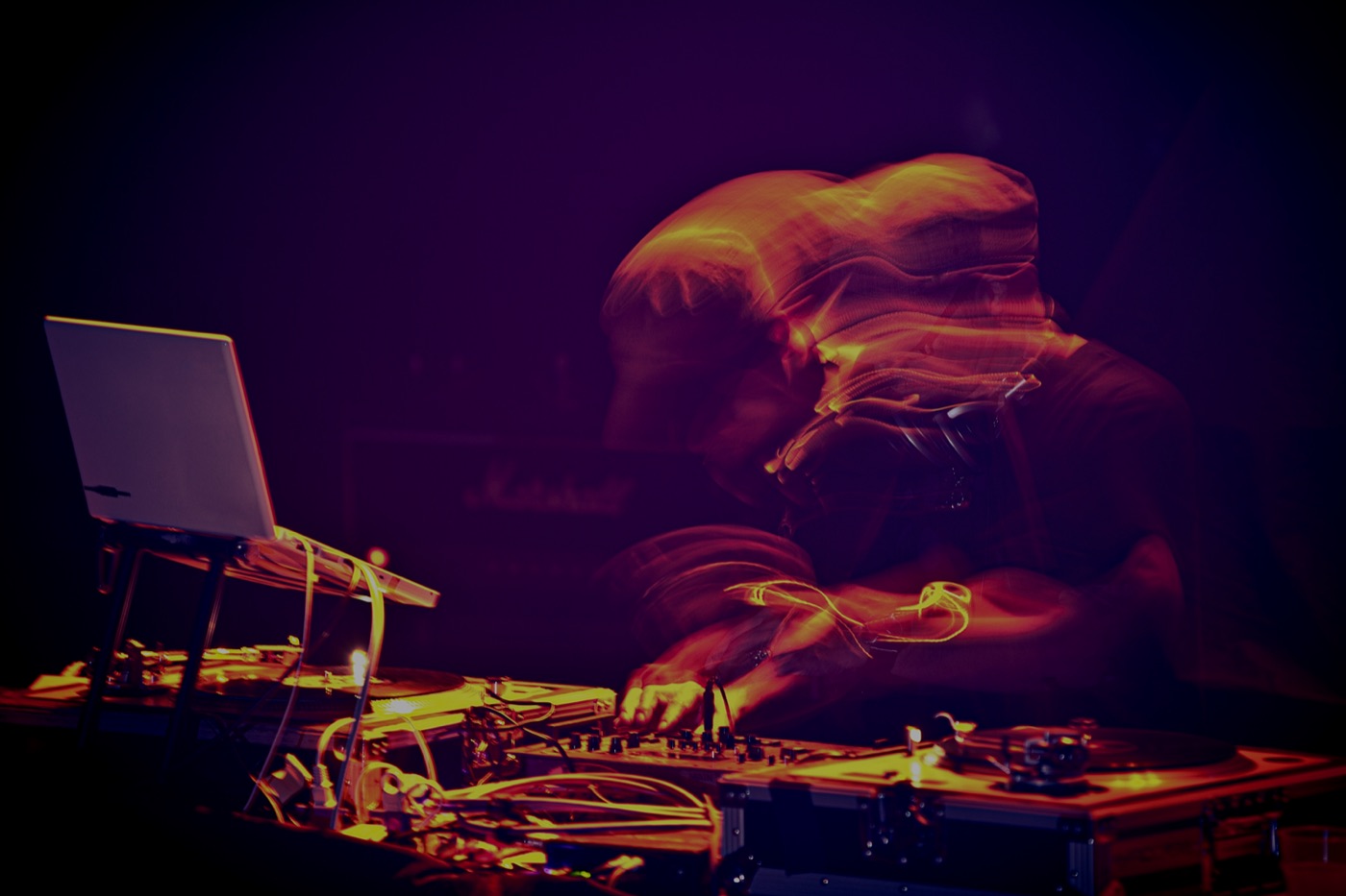 A DJ's hands on the mixer in purple light